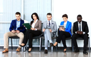 five people sitting in a row waiting for an interview at an office