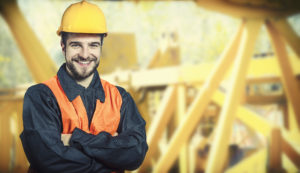 a man with a hard hat with his arms crossed standing in front of a construction site