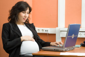 pregnant woman at work researching worker's rights on her laptop