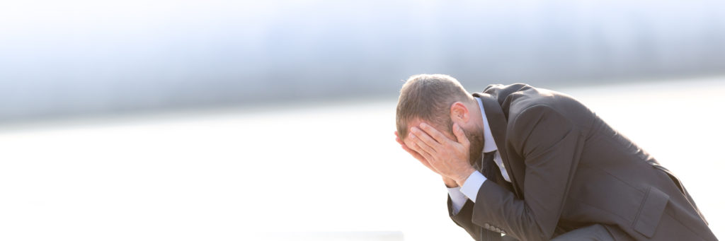 unhappy businessman holding his head in his hands after becoming a victim of employer discrimination