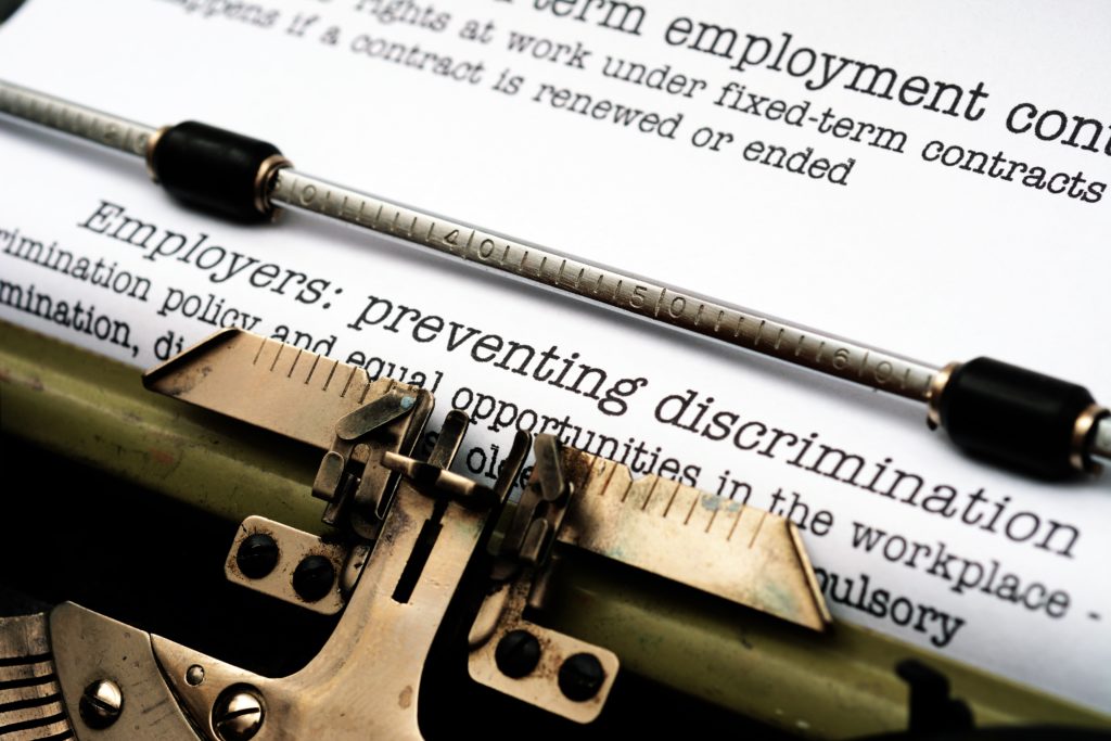 paper in typewriter stating "Employers: preventing discrimination"